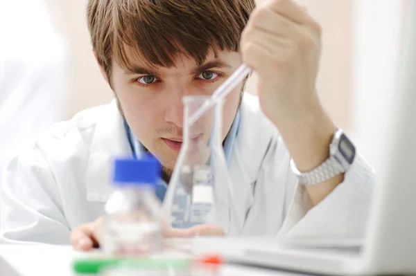 Científico médico joven que trabaja en laboratorio moderno, investigación con tubos y nota — Foto de Stock