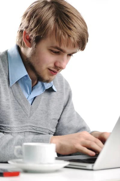 Un joven usando un portátil. Escribiendo. Taza de café al lado . — Foto de Stock