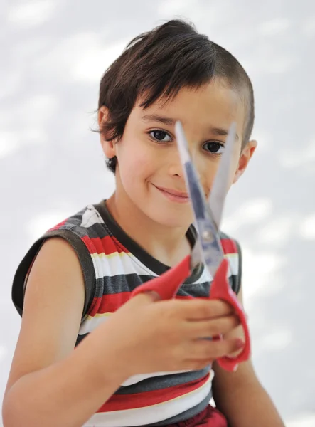 Enfant couper les cheveux à lui-même avec des ciseaux, regard drôle — Photo