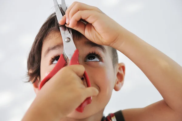 Niño cortar el pelo a sí mismo con tijeras, mirada divertida —  Fotos de Stock