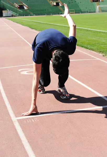 Jeune athlète masculin est au début du tapis roulant au stade — Photo