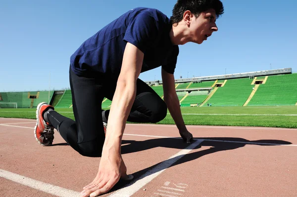Junge männliche Athletin am Start auf dem Laufband im Stadion — Stockfoto