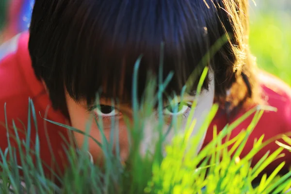 Pequeño niño lindo que pone en la hierba de verano de la mañana con luz hermosa natural — Foto de Stock