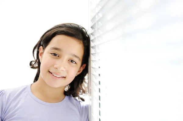 Šťastná dívka vnitřních, opíraje se o okna — Stock fotografie