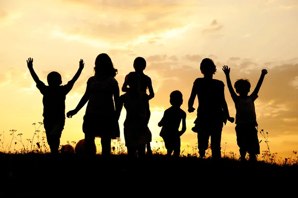Силует, Група щасливих дітей, що грають на луг, захід сонця, літній час — стокове фото
