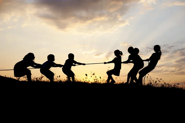 Silhueta, grupo de crianças felizes brincando no prado, pôr do sol, verão — Fotografia de Stock