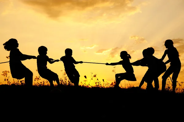 Σιλουέτα, ομάδα χαρούμενα παιδιά να παίζουν σε Λιβάδι, ηλιοβασίλεμα, καλοκαίρι — Φωτογραφία Αρχείου