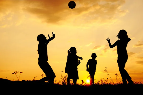 Siluet, grup mutlu çocuklar oynarken çayır, günbatımı, yaz — Stok fotoğraf