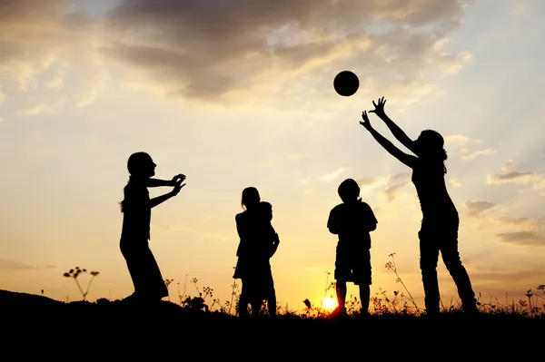 Silhueta, grupo de crianças felizes brincando no prado, pôr do sol, verão — Fotografia de Stock