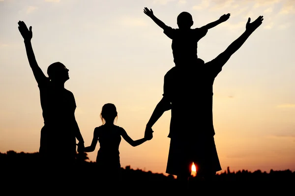 Silhouette, enfants heureux avec mère et père, famille au coucher du soleil, été — Photo