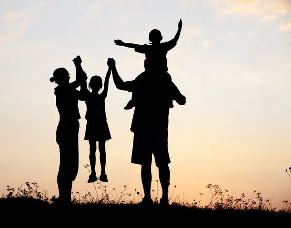 Silhueta, crianças felizes com mãe e pai, família ao pôr do sol, verão — Fotografia de Stock
