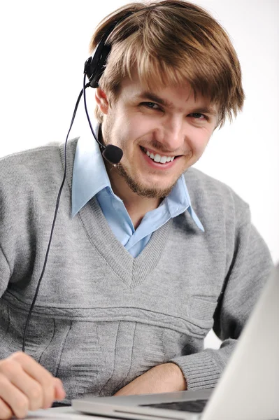 Egy fiatal férfi portréja fejhallgatóval egy laptop előtt. — Stock Fotó