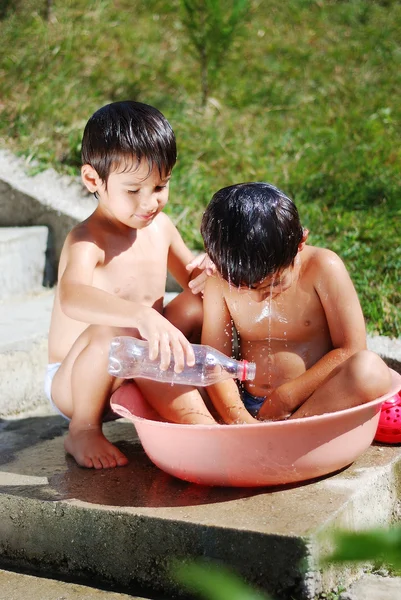 Mycket söta barn leker med vatten utomhus — Stockfoto
