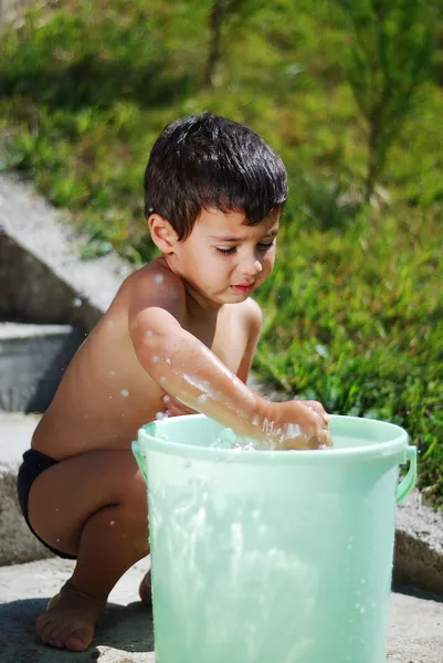 Очень милый ребенок, играющий с водой на открытом воздухе — стоковое фото