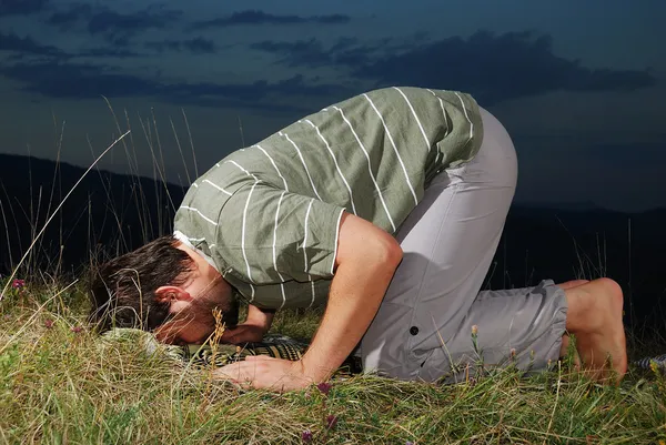 若いイスラム教徒の男性は、草原に祈って日没時間 — ストック写真