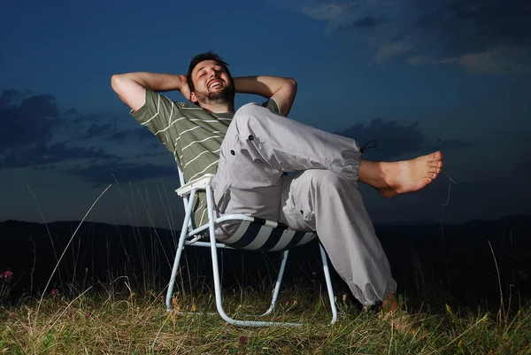 Jovem homem muçulmano está sentado no prado, hora do pôr do sol — Fotografia de Stock