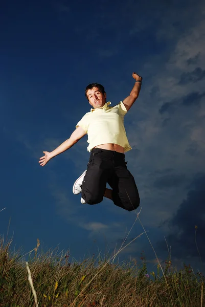 Молодой счастливый человек прыгает по зеленому лугу — стоковое фото