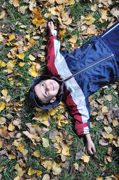 Sonbahar yerde yatan küçük şirin çocuk — Stok fotoğraf