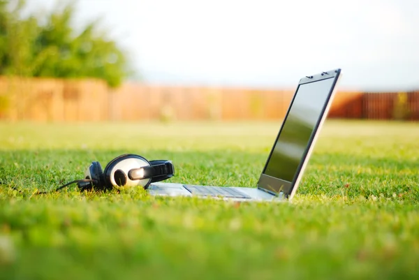 Laptop e fone de ouvido no prado — Fotografia de Stock