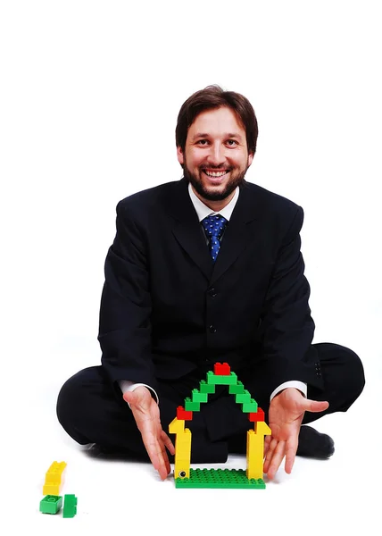 Young mane wearing suit is making a house with cubes toys — Stock Photo, Image