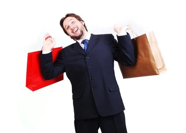 Vonzó fiatalember visel öltönyt és a gazdaság bevásárló táskák — Stock Fotó