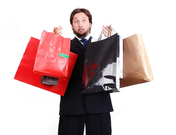 Joven atractivo hombre usando traje y sosteniendo bolsas de compras — Foto de Stock