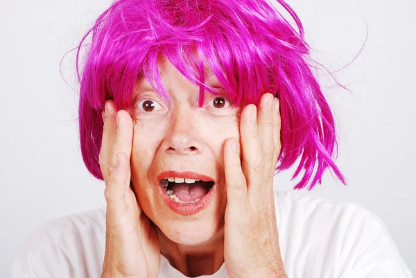 Mulher sênior com cabelo rosa e gesto facial — Fotografia de Stock
