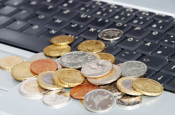 Muchas monedas en un solo lugar en el teclado portátil — Foto de Stock