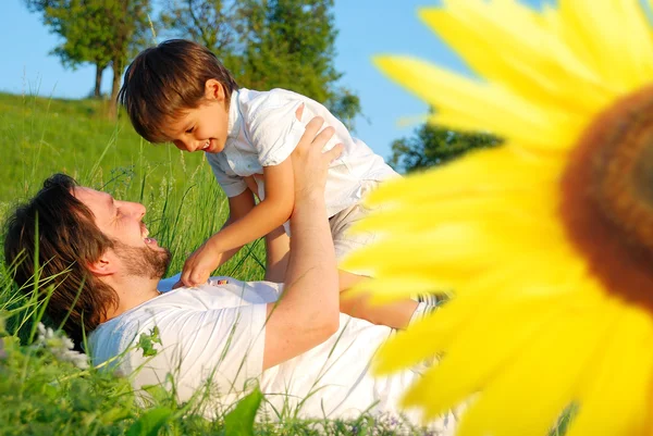 Happy childhool on green meadow, behind sunflower — Stock Photo, Image
