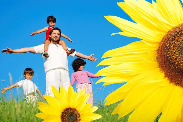 Glückliche Kindheit auf der grünen Wiese, hinter Sonnenblumen — Stockfoto