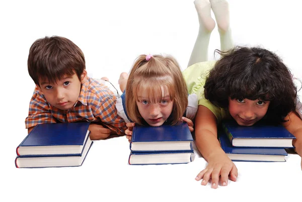 Troje dzieci ustanawiające na książki, na białym tle — Zdjęcie stockowe