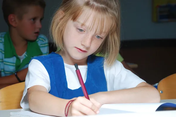 Menina bonito pouco em sala de aula, escrita — Fotografia de Stock