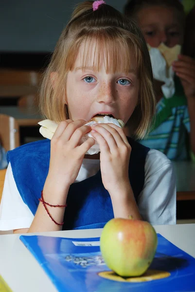 Little cute girl in classroom, eating — Stock Photo, Image