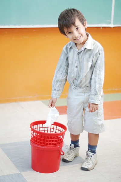 Liten söt pojke kasta papper i papperskorgen — Stockfoto