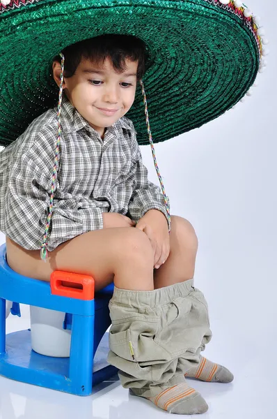 Ragazzo carino con cappello messicano sulla testa, seduto sul water — Foto Stock