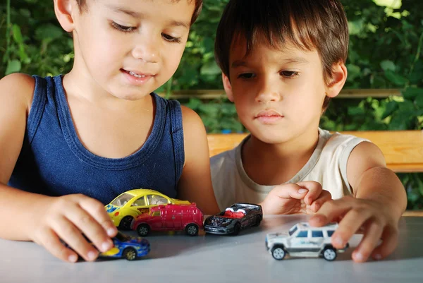 Crianças brincando com carros brinquedos ao ar livre na hora de verão — Fotografia de Stock