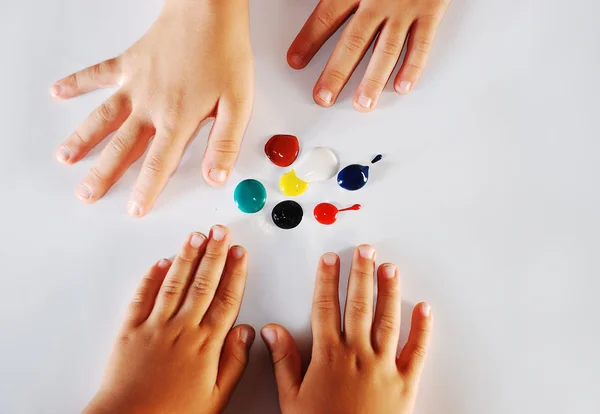 Bambini piccole mani che giocano con i colori su sfondo bianco — Foto Stock