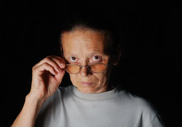 Middle aged woman with glasses with dark background — Stock Photo, Image