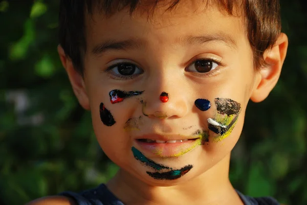 Pequeno garoto bonito com cores em seu rosto — Fotografia de Stock