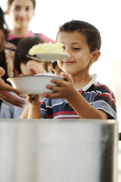 Crianças famintas no campo de refugiados, distribuição de alimentos humanitários Fotografias De Stock Royalty-Free