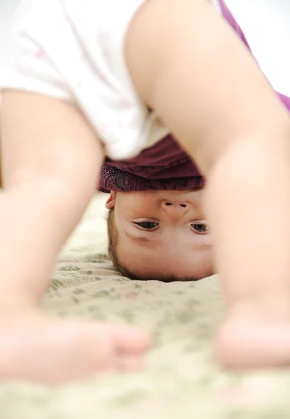 Baby boy playing upside down in bedroom Stock Image