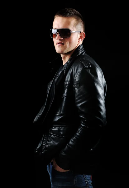 Moda elegante jovem Homem retrato com jaqueta de couro no fundo preto Imagem De Stock