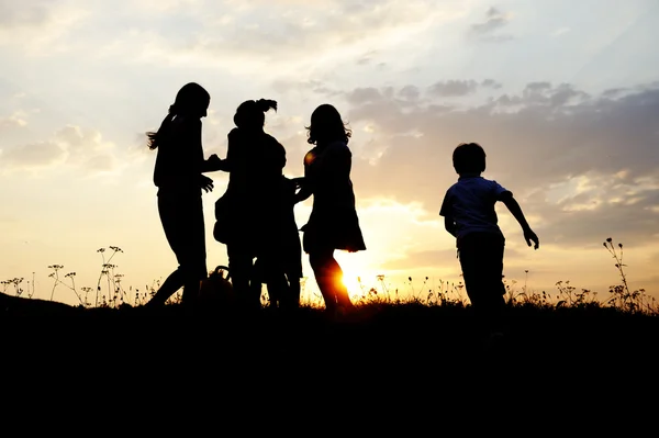 シルエット、幸せな子供のプレー グループ草原、日没、夏 ストックフォト