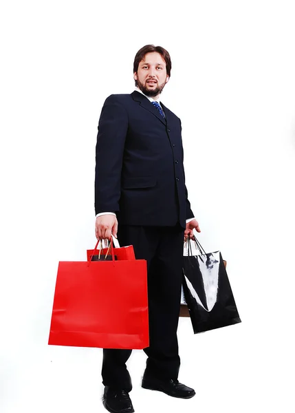 Vonzó fiatalember visel öltönyt és a gazdaság bevásárló táskák Stock Fotó