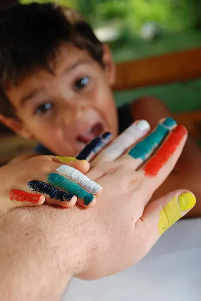 Diversi colori sulle dita di bambino e padre, all'aperto Fotografia Stock