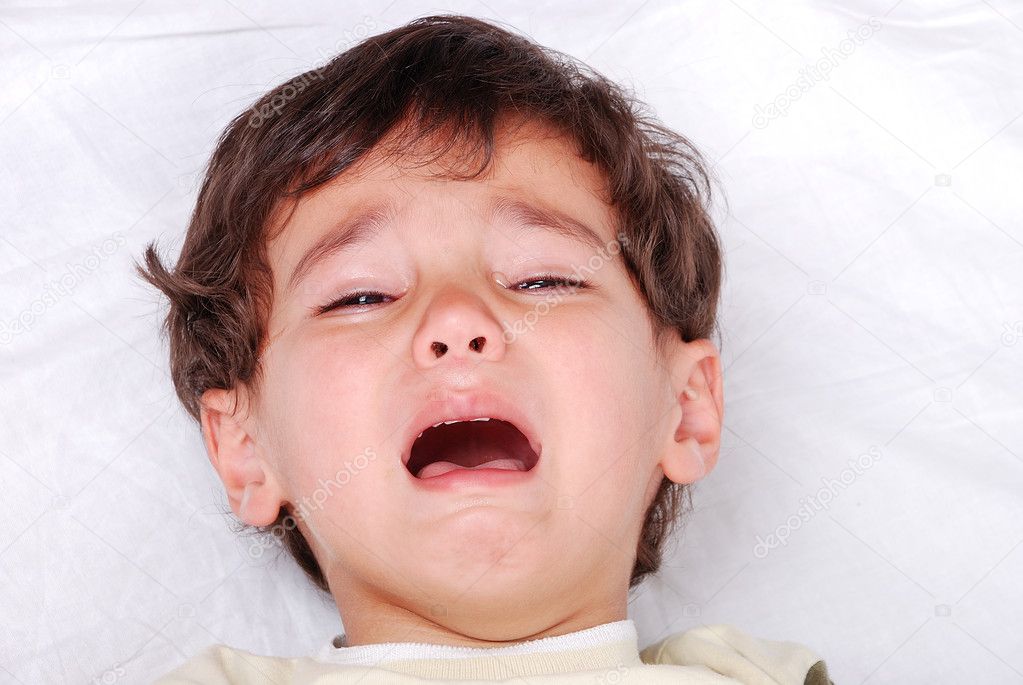 Little cute kid is crying on white sheet
