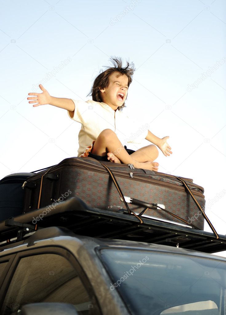 Little boy traveling on bags, the top of the car