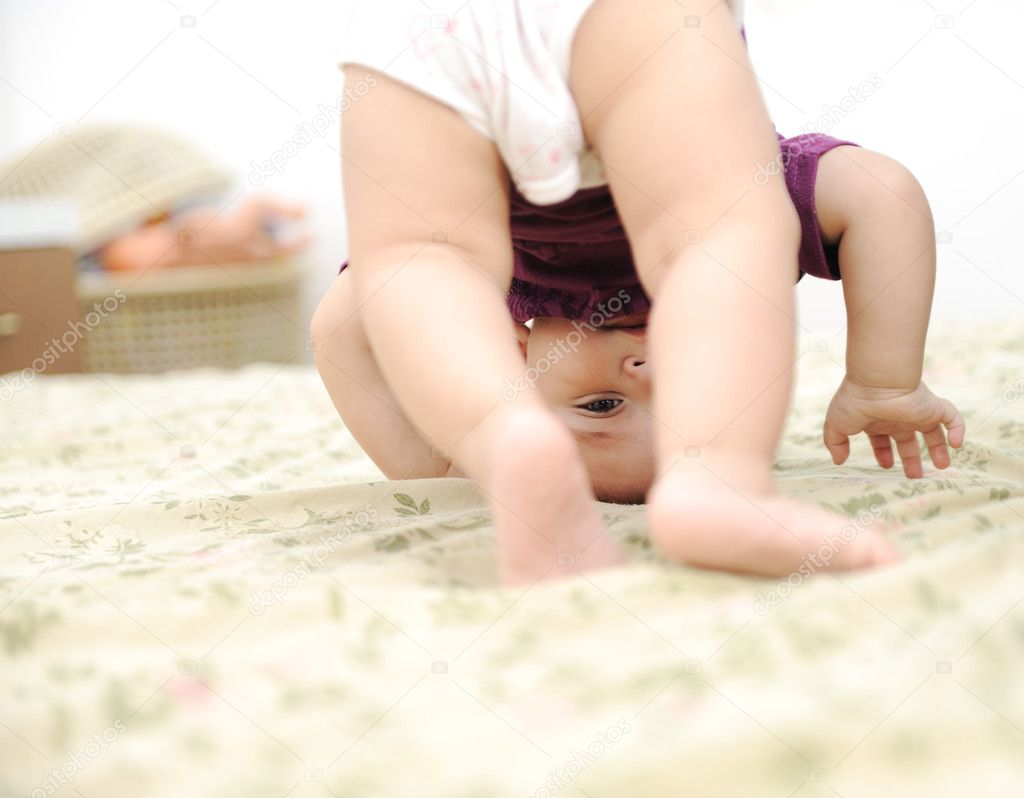 Baby boy playing upside down in bedroom