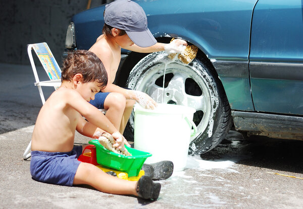 A little cute kid is cleaning car, outdoor