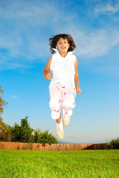 Lilla flickan hoppar mot vacker himmel — Stockfoto